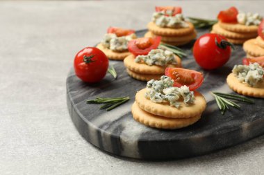 Lezzetli krakerler mavi peynirli, biberiyeli ve domatesli gri desenli masa, yakın plan.