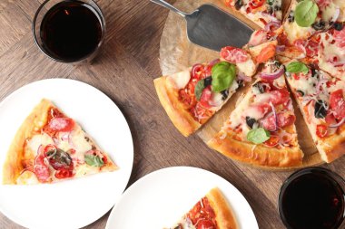 Tahta masada servis edilen ince tütsülenmiş sosisli lezzetli pizza dilimleri.