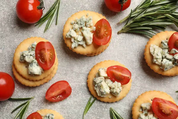 Lezzetli krakerler mavi peynirli, biberiyeli ve domatesli gri desenli masa, düz.