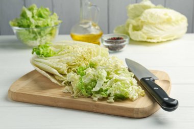 Beyaz ahşap masada Çin lahanası ve bıçağı kes, yakın plan.