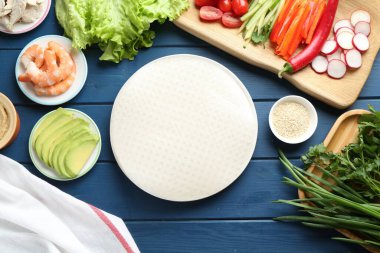 Pirinç kağıt çarşaflar ve mavi ahşap masa üzerindeki farklı malzemeler.