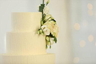 Bulanık arkaplanda çiçek dekoru olan nefis düğün pastası, mesaj için yer. Bokeh etkisi