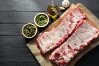 Çiğ domuz pirzolası, deniz tuzu, yağ, sarımsak ve otlar siyah ahşap masa üzerinde, düz yatıyordu.