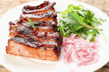 Lezzetli pirzola, soğan ve roka ahşap masada, yakın plan.