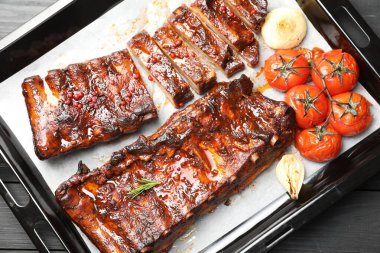 Lezzetli kaburgalar, fırında soğan ve kurutulmuş domatesler, gri ahşap masa, üst manzara.