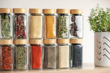 Kapalı alandaki ahşap raftaki kavanozlardaki farklı aromatik baharatlar.