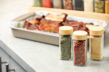 Kavanozlarda farklı aromatik baharatlar ve açık gri tezgahlarda farklı yemekler.