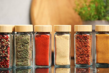 Ayna yüzeyindeki kavanozlarda farklı aromatik baharatlar, yakın plan.