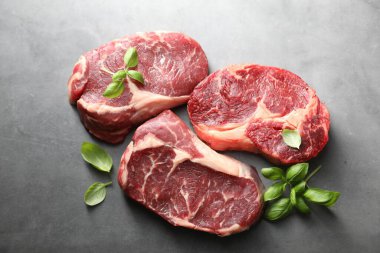Çiğ et ve fesleğen parçaları gri masada, düz yerde yatıyordu.