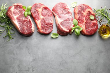 Çiğ et ve baharat parçaları gri masada, düz yerde. Metin için boşluk