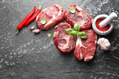 Koyu masa üzerinde çiğ et ve baharat parçaları, düz. Metin için boşluk