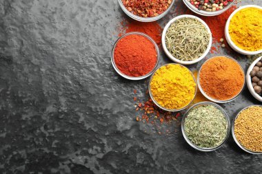 Tabaklardaki farklı aromatik baharatlar karanlık masada, düz yerde. Metin için boşluk