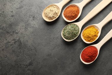 Gri masadaki kaşıklarda bir sürü farklı baharat var. Metin için boşluk