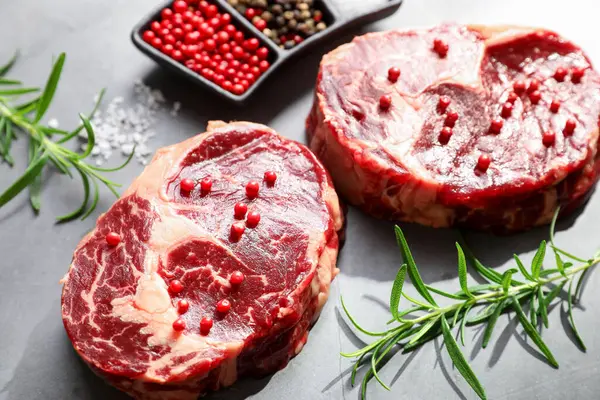 Gri desenli masa üzerinde çiğ et ve baharat parçaları, yakın plan.