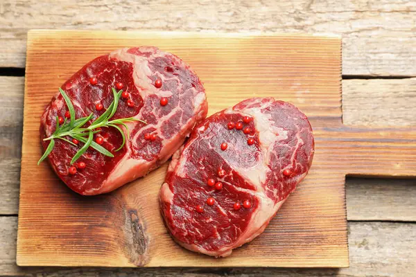 Ahşap masada çiğ et ve baharat parçaları.