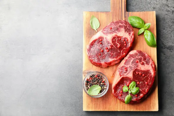 Gri desenli masa üzerinde çiğ et ve baharat parçaları, üst manzara. Metin için boşluk