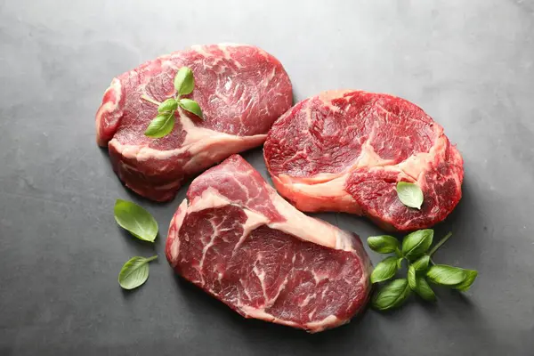 Çiğ et ve fesleğen parçaları gri masada, düz yerde yatıyordu.