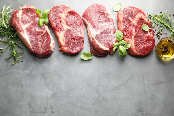 Çiğ et ve baharat parçaları gri masada, düz yerde. Metin için boşluk