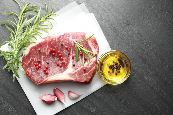 Bir parça çiğ et ve baharat siyah masada, düz yerde. Metin için boşluk