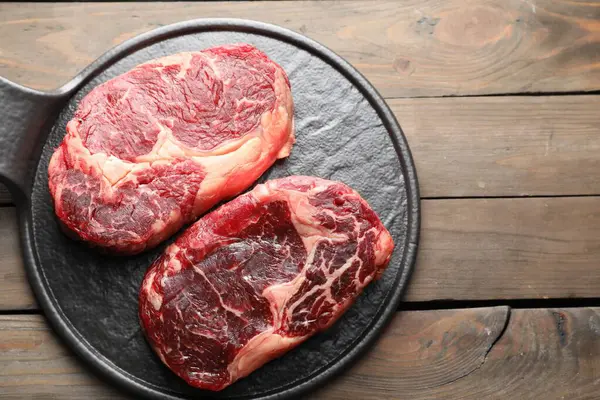 Ahşap masada çiğ et parçaları, üst manzara. Metin için boşluk