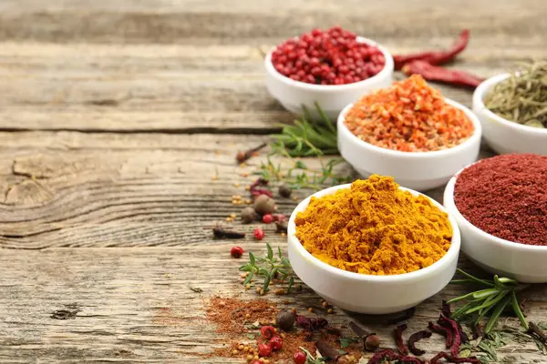 Ahşap masada farklı aromatik baharatlar, yakın plan. Metin için boşluk