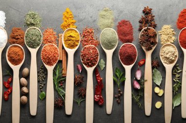 Gri masadaki kaşıklardaki farklı baharatlar düzdü.
