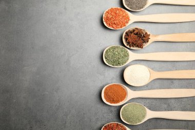 Gri masadaki kaşıklarda bir sürü farklı baharat var. Metin için boşluk