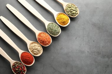 Gri masadaki kaşıklarda bir sürü farklı baharat var. Metin için boşluk