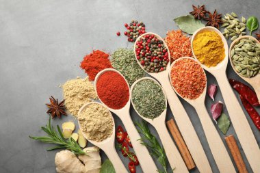 Gri masadaki kaşıklardaki farklı baharatlar düzdü.