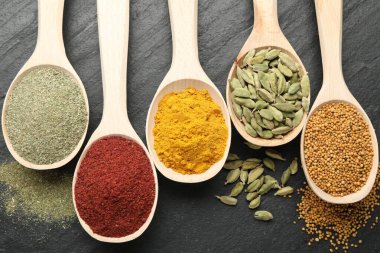 Siyah masadaki kaşıklardaki farklı aromatik baharatlar.