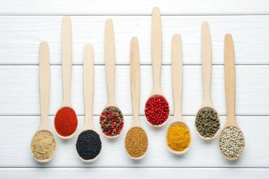 Beyaz ahşap masadaki kaşıklardaki farklı aromatik baharatlar.