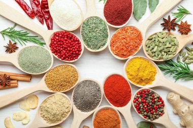 Beyaz ahşap masadaki kaşıklardaki farklı aromatik baharatlar.