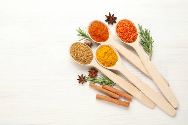 Beyaz ahşap masadaki kaşıklardaki farklı aromatik baharatlar. Metin için boşluk