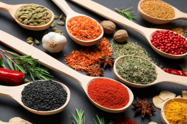 Siyah masada kaşıklardaki farklı aromatik baharatlar, yakın plan.