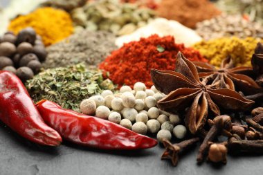 Gri masada farklı aromatik baharatlar, yakın plan.