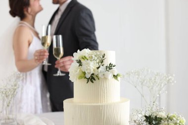 Evde evli bir çift, düğün pastasına ve masadaki bukete odaklanıyor.