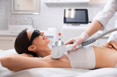 Güzellik salonunda lazer tüy dökme işlemi sırasında gülümseyen kadın.