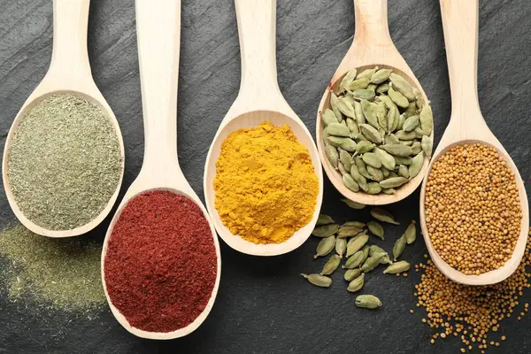 Siyah masadaki kaşıklardaki farklı aromatik baharatlar.
