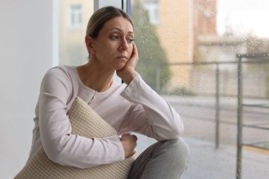 Depresyondaki kadın pencereden dışarı bakıyor, mesaj için boşluk var.