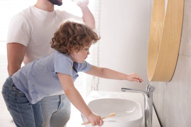 Babası ve oğlu banyoda diş fırçasıyla, yakın plan.