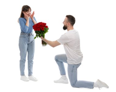 Adam beyaz arka planda sevgilisine kırmızı gül buketi sunuyor.