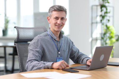 Ofiste dizüstü bilgisayarla çalışan gülümseyen mühendis.