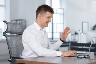 Ofisteki bilgisayarla video görüşmesi yapan bir adam.