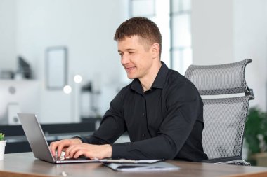 Ofiste masada dizüstü bilgisayarda çalışan adam