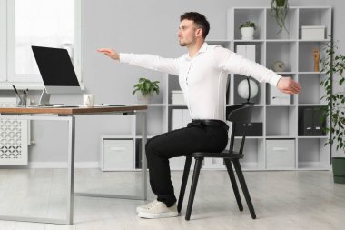 Ofiste sandalyeye uzanan yakışıklı adam.