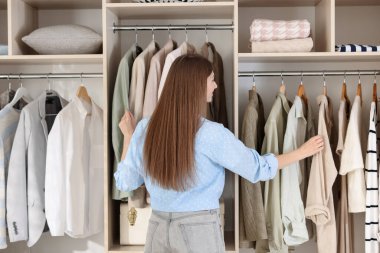 Moda stilisti. Stüdyoda, arka planda kıyafet seçiyor.