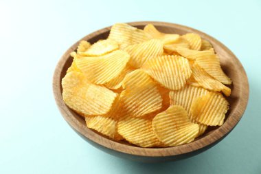 Açık mavi arka planda, kasede patates cipsi, yakın plan.