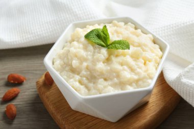 Lezzetli sütlaç kasede, badem ve nane şekeri ahşap masada, yakın plan.