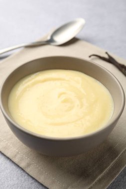 Lezzetli vanilyalı puding, kapsüller ve kaşık açık gri masada, yakın plan.