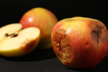 Siyah arkaplanda kesilmiş çürük elmalar, yakın plan.